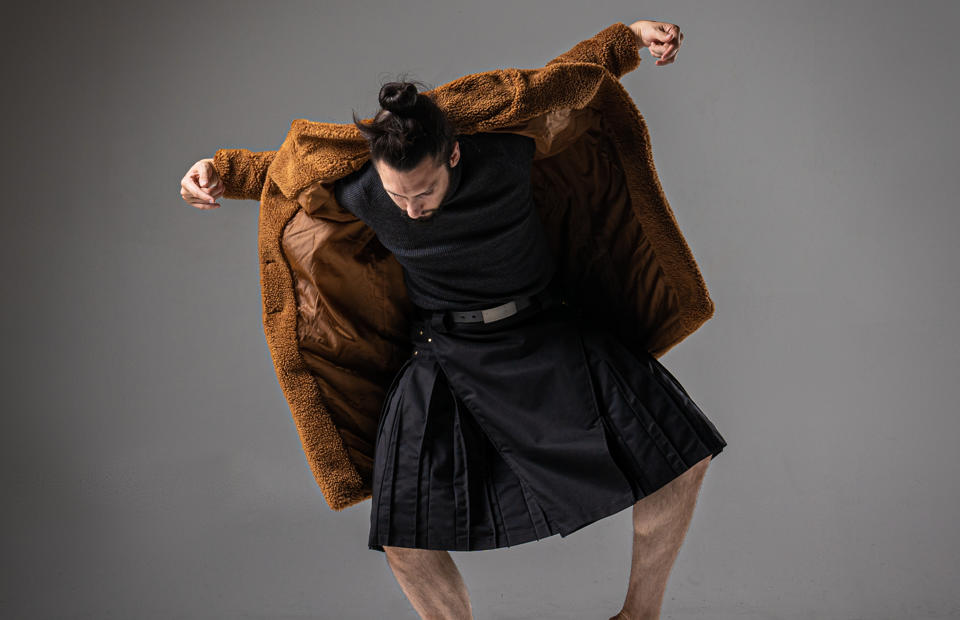push/FOLD composer-choreographer Samuel Hobbs in a brown furry jacket and kilt holding a delicate and contorted pose.