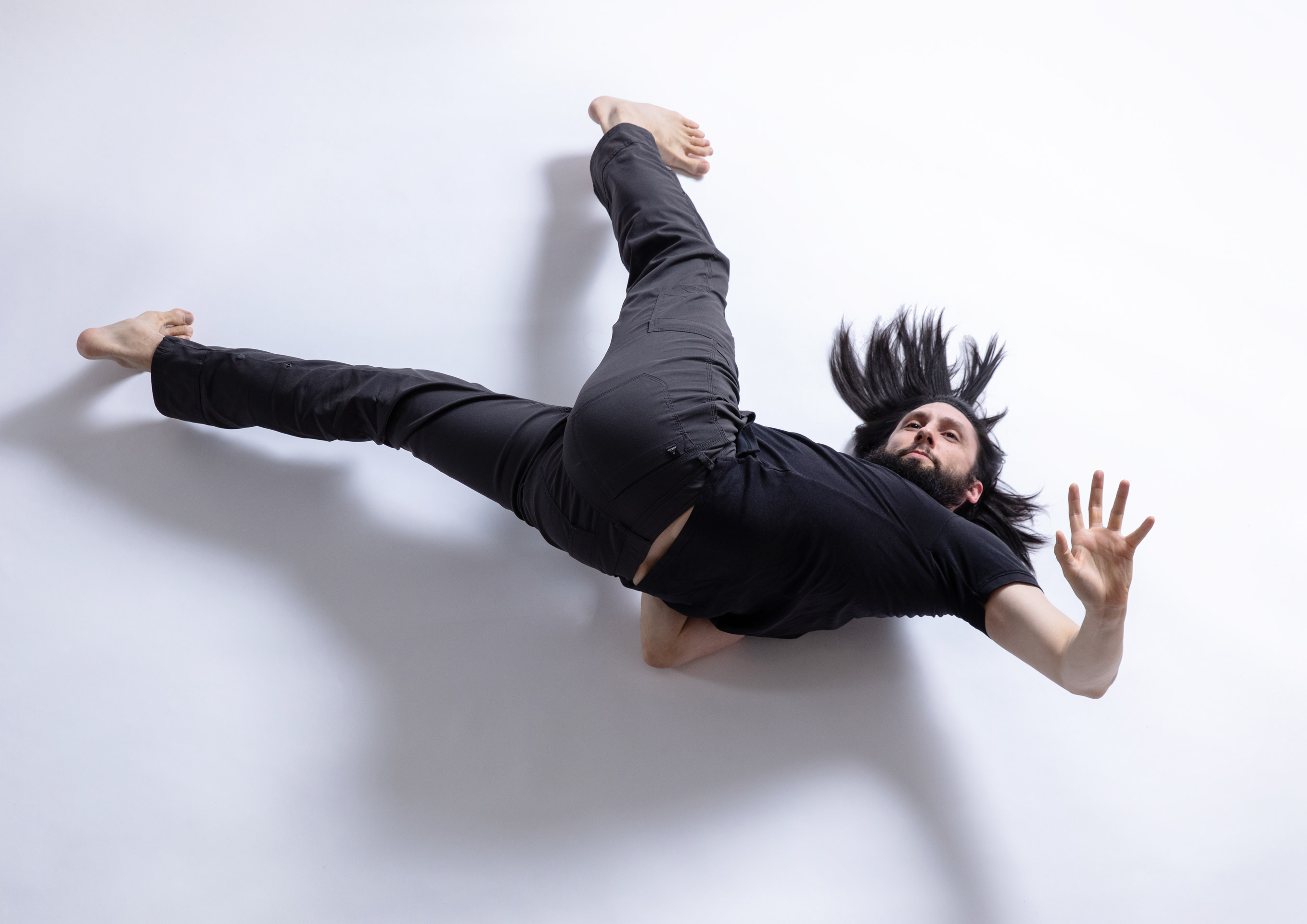 push/FOLD's artistic director Samuel Hobbs inverts on their shoulders with long legs while looking up at Tempos Circus Studio in Portland, Oregon | Photography: Gregory Bartning