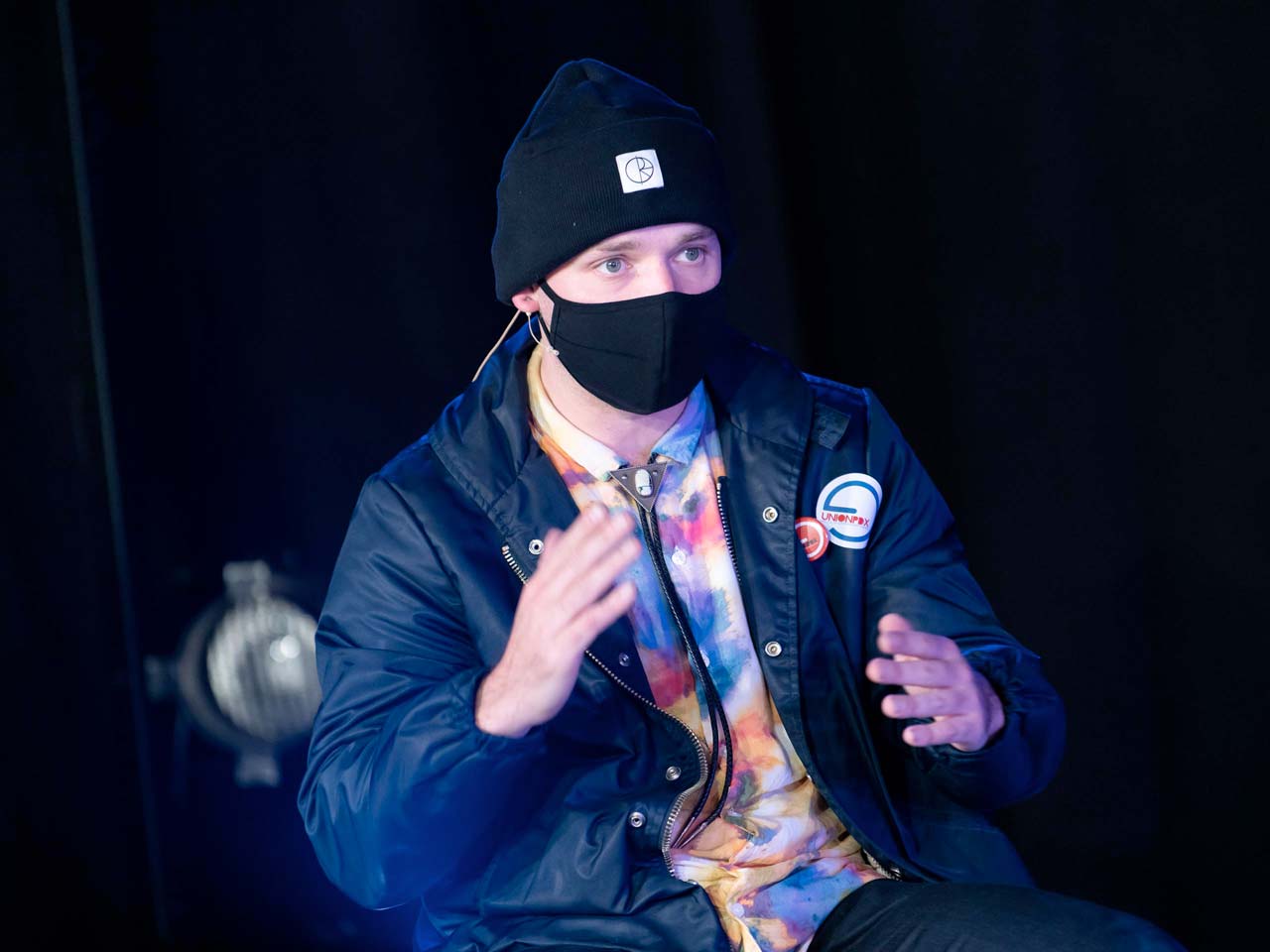 Union PDX - Festival:20 artist Conrad Kaczor wearing a blue jacket and tie dye shirt speaks at the live-streamed artist discussion at Polaris Dance Theatre in Portland, Oregon | Photography: Jingzi Zhao